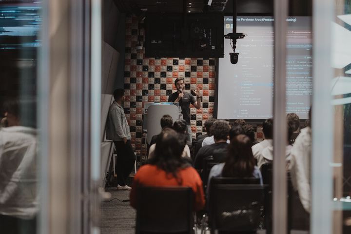 The room seen through the glass wall, a talk under way.